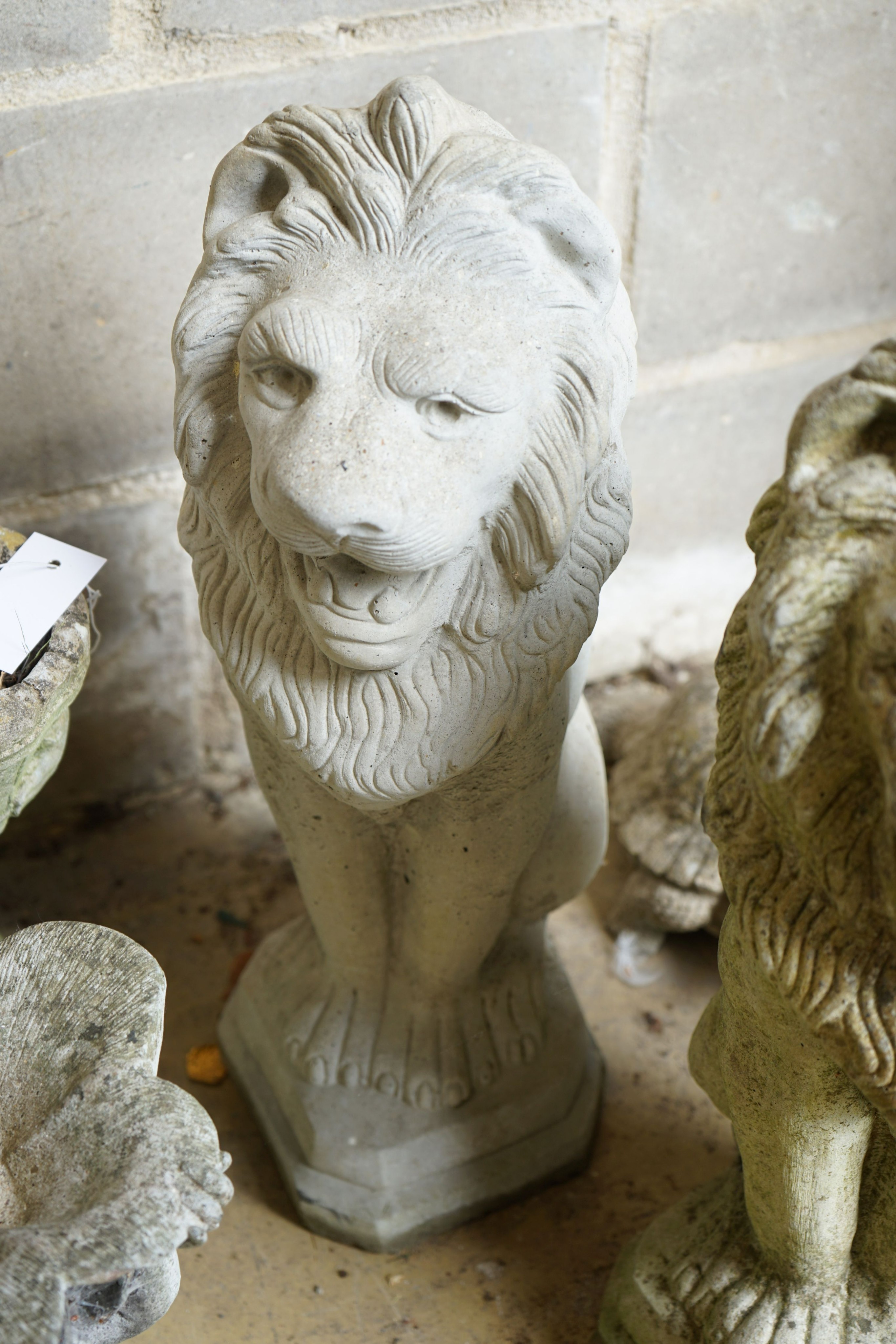 A pair of reconstituted stone seated lion garden ornaments, height 56cm